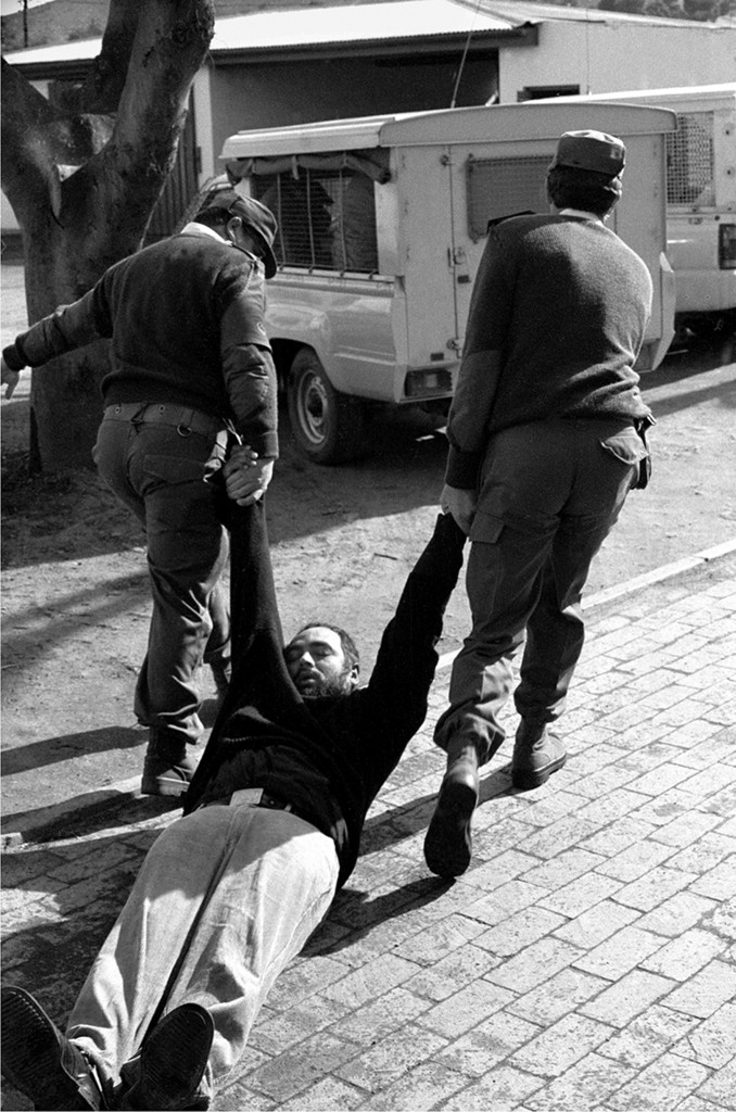 Rev. Michael Weeder being dragged after a teargas attack, June 1990.  Photograph by Benny Gool